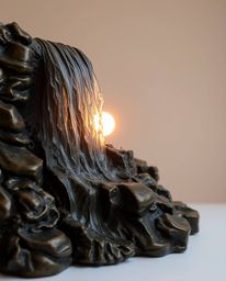An exquisite antique bronze sculpture of a waterfall with a setting sun. This piece exhibits a beautiful patina finish and is