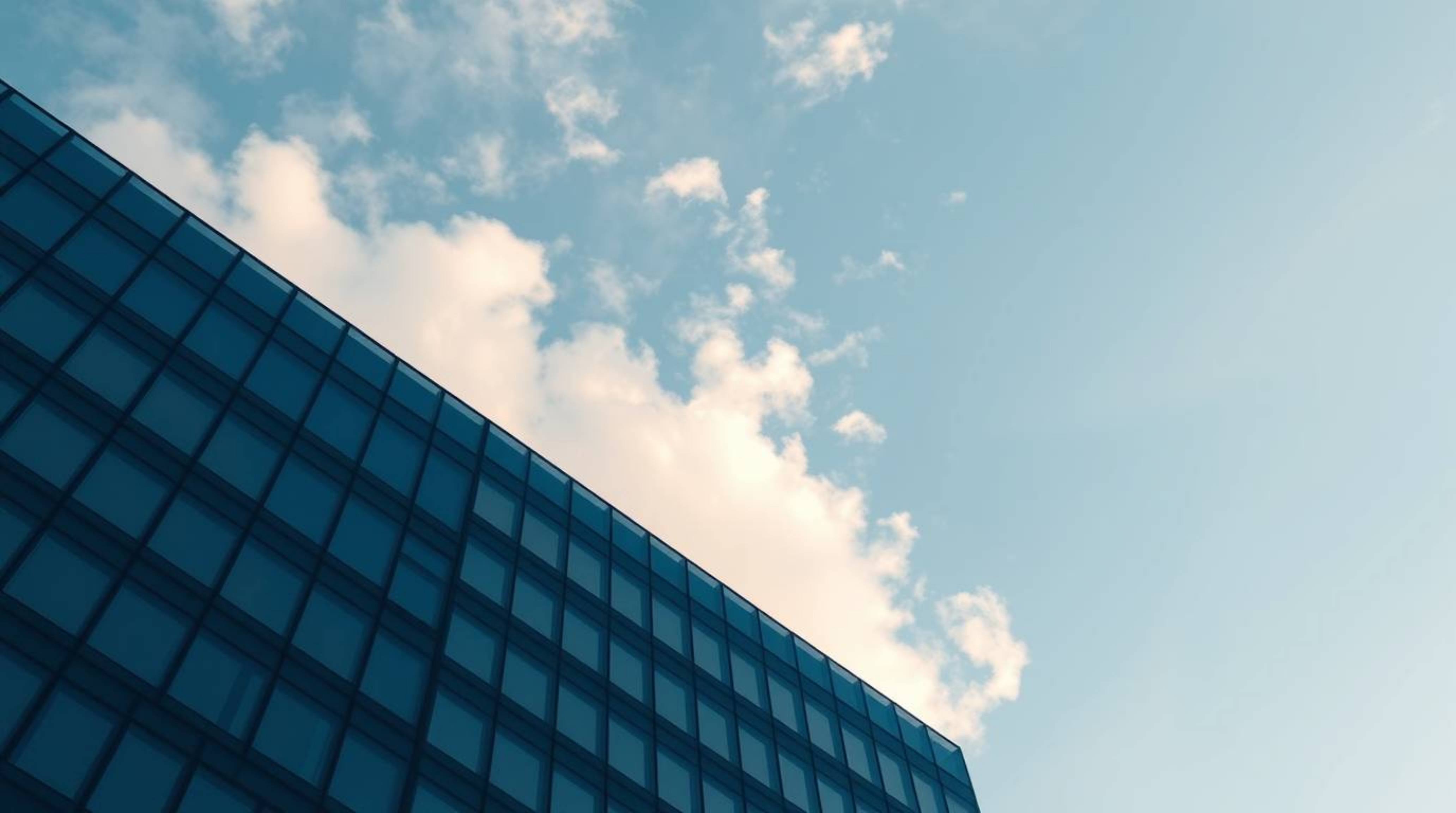 A high-resolution stock photo showcases a modern glass building seemingly dissolving into the sky, where soft clouds merge se