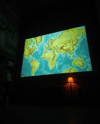 Discover a captivating image: a low-angle view of a brightly glowing map projected onto the walls of an old study.  The scene
