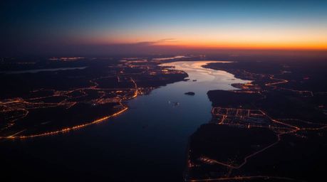 Capture the breathtaking beauty of a river delta bathed in twilight's embrace, viewed from a bird's eye perspective. Witness 