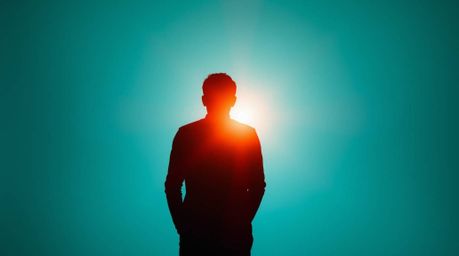 A captivating image featuring a silhouetted figure set against a deep teal abstract gradient background. The artwork incorpor
