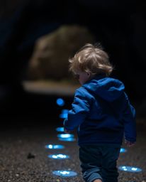 A captivating long exposure photograph depicts a child with light brown hair and freckles, clad in a blue jacket, venturing i
