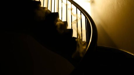 A captivating close-up showcases a surreal, winding stairway crafted from smoke and light.  The image, shot against a bright 