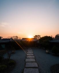A long-exposure photograph of a sunset over a serene Zen garden, capturing ethereal light trails and creating a mystical atmo