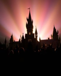 Discover a captivating image of a magical school silhouetted against a vibrant, iridescent light source.  Young wizards popul