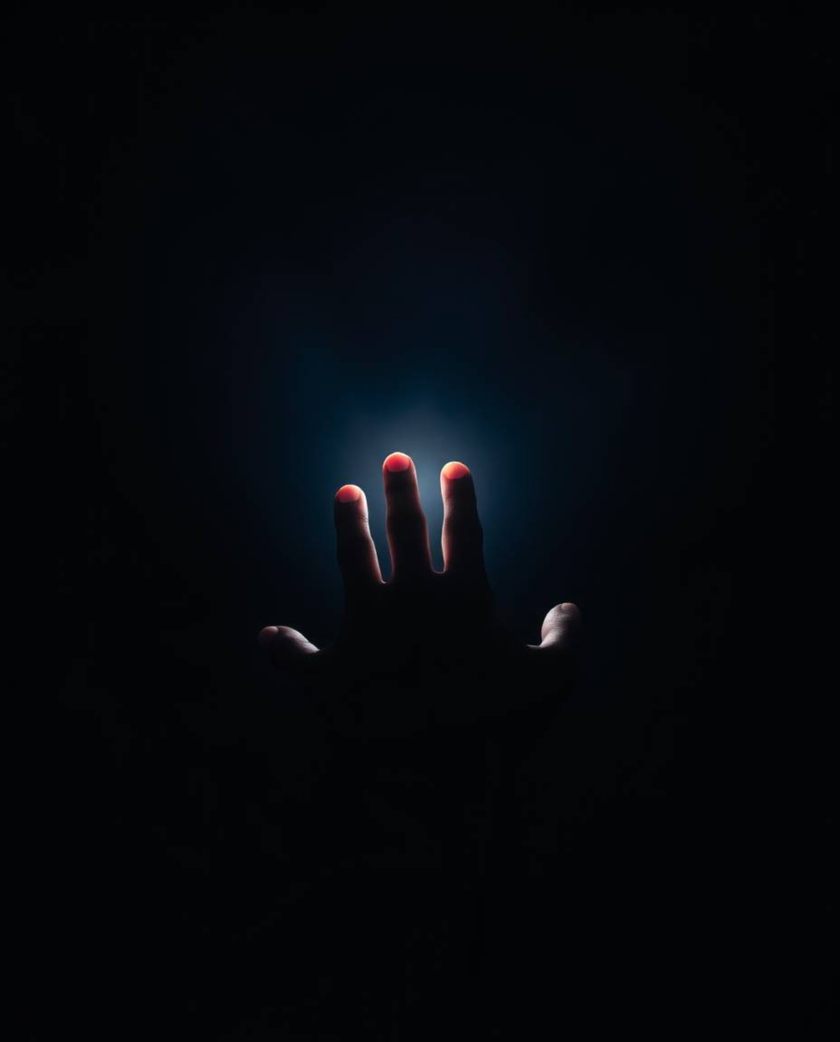 A captivating long exposure photograph depicts a hand gently reaching towards a soft, diffused light emanating from the darkn