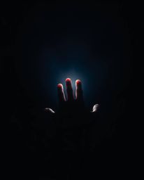 A captivating long exposure photograph depicts a hand gently reaching towards a soft, diffused light emanating from the darkn