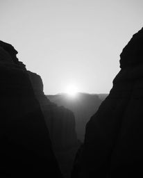 A classic black and white image offers a timeless and elegant depiction of a sunset illuminating sandstone cliffs in a canyon