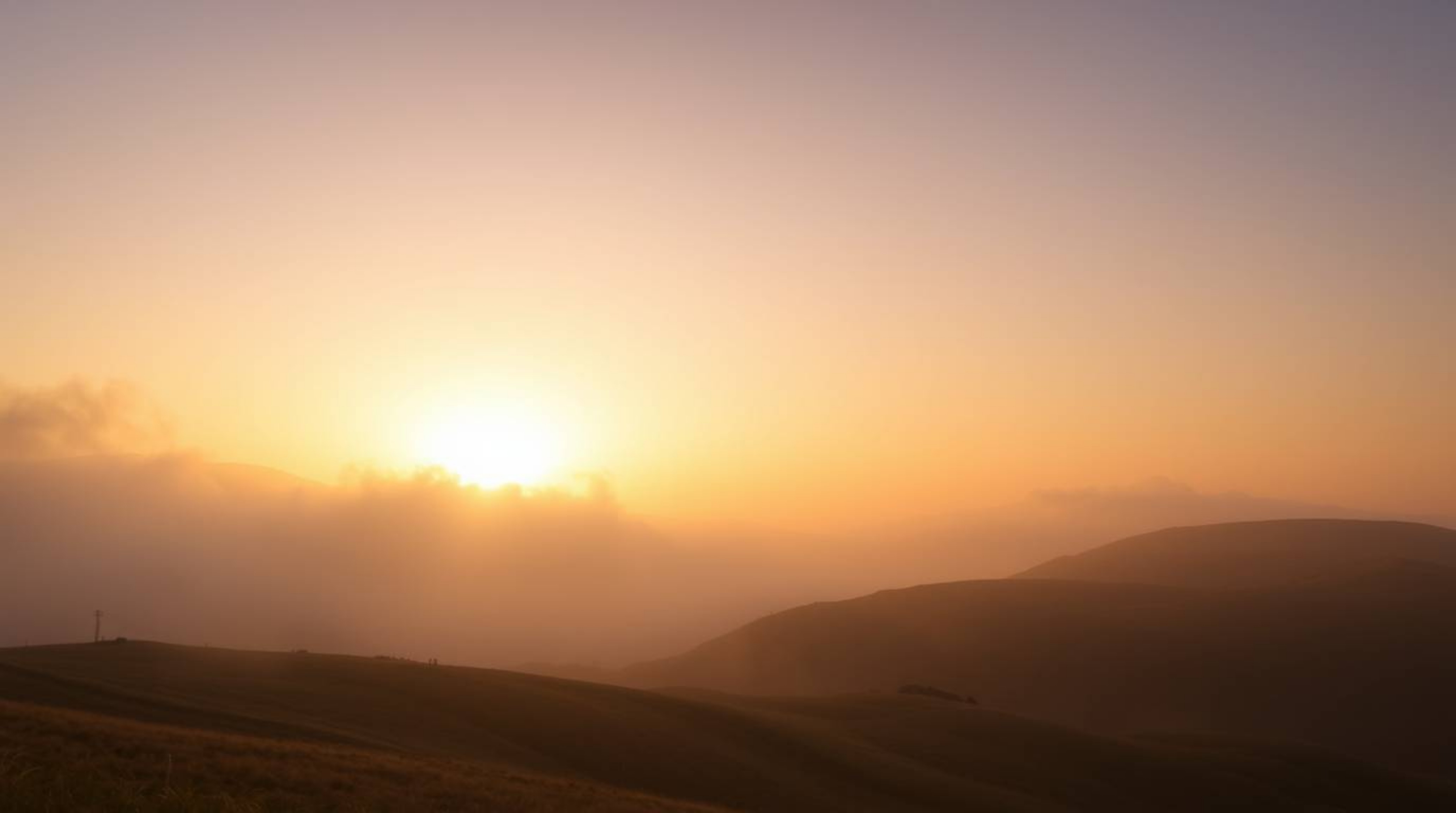 Experience a dramatic and captivating landscape featuring fog-covered hills bathed in the warm, natural earth tones of brown 