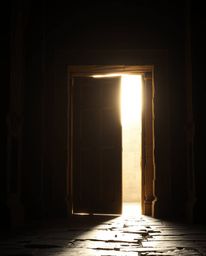 A dramatic cinematic style image featuring an ancient doorway glowing with runes, silhouetted against a bright light source. 