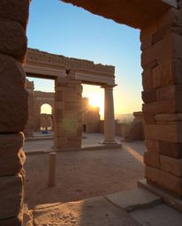 A scene of a sunset casting shadows through ancient stone ruins, characterized by natural earth tones. The palette consists o