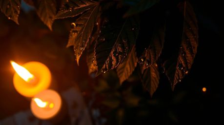 A captivating bird's-eye view showcasing the warm illumination of candlelight reflecting a stunning sunset in delicate raindr