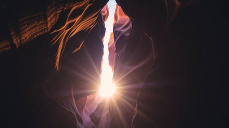 Experience the breathtaking beauty of creative light art illuminating a rocky canyon during a warm sunset. This captivating i