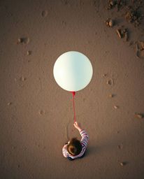 This image depicts a child holding a balloon, captured from an overhead bird's eye view, offering a top-down perspective on a