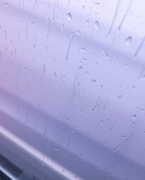 A captivating high-angle shot depicts a wet, rainy scene with a soft gradient texture blending pink, blue, and violet hues. T