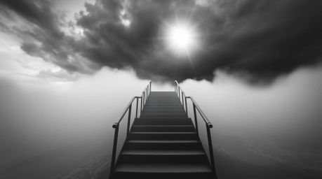 A dramatic black and white close-up depicts a staircase rising from the ocean into a stormy sky, illuminated by a divine sunb