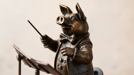 Discover a captivating cast bronze sculpture of a pig character majestically conducting an orchestra.  The antique finish and