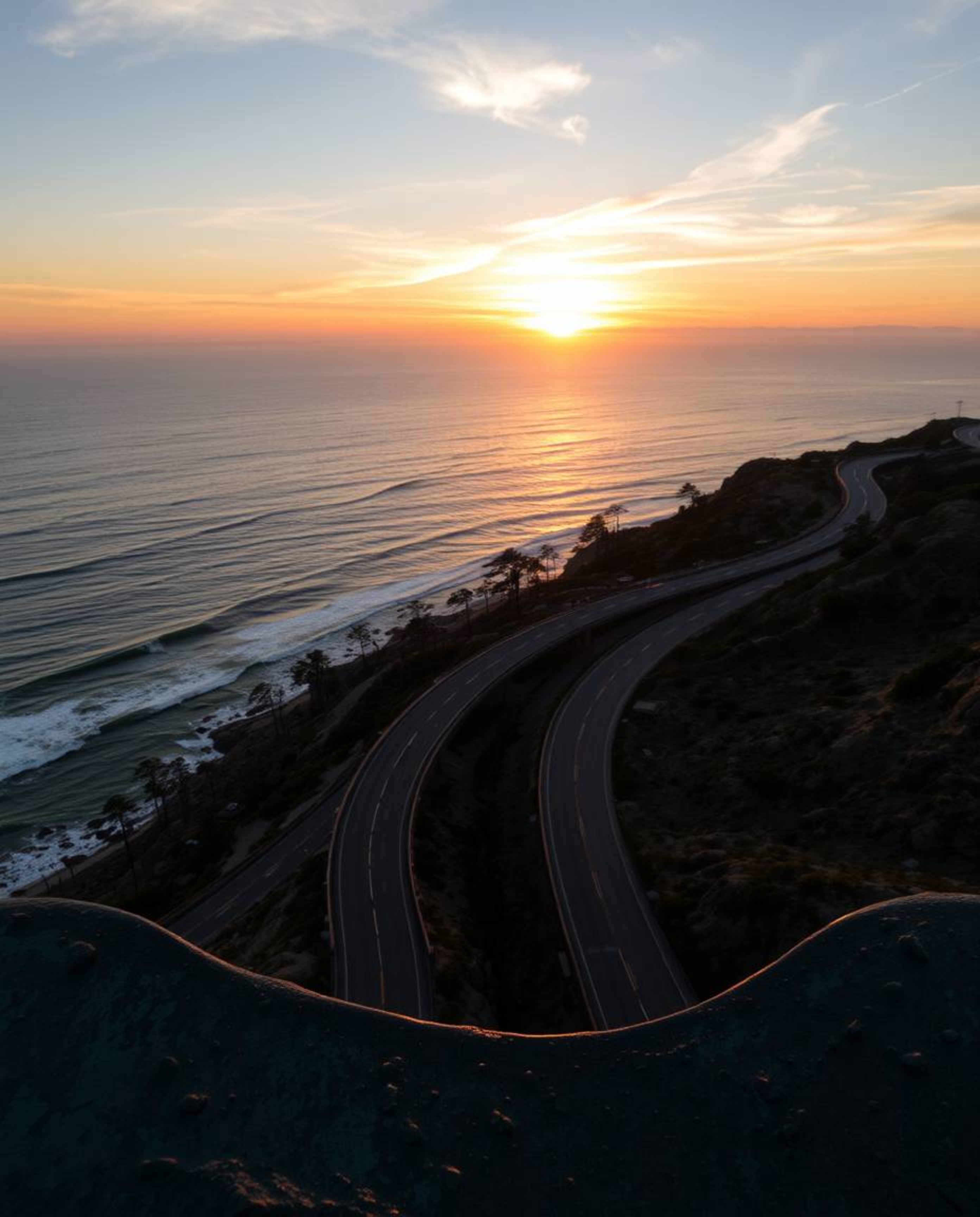 This is a cast bronze sculpture that provides an overhead bird’s eye view of a sunset sky over a winding coastal highway. The
