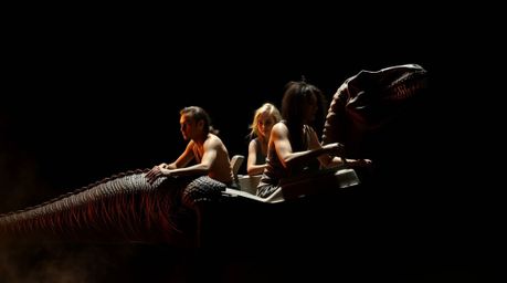 Experience a visually stunning scene of a prehistoric family with deep skin tones riding a dinosaur car, immersed in a cinema