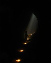 A captivating image depicting a child venturing into a cave, guided by glowing footsteps. The scene is bathed in contrasting 
