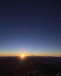 This is a high-resolution stock photo capturing a breathtaking sunset as viewed from a high alpine peak. With its professiona
