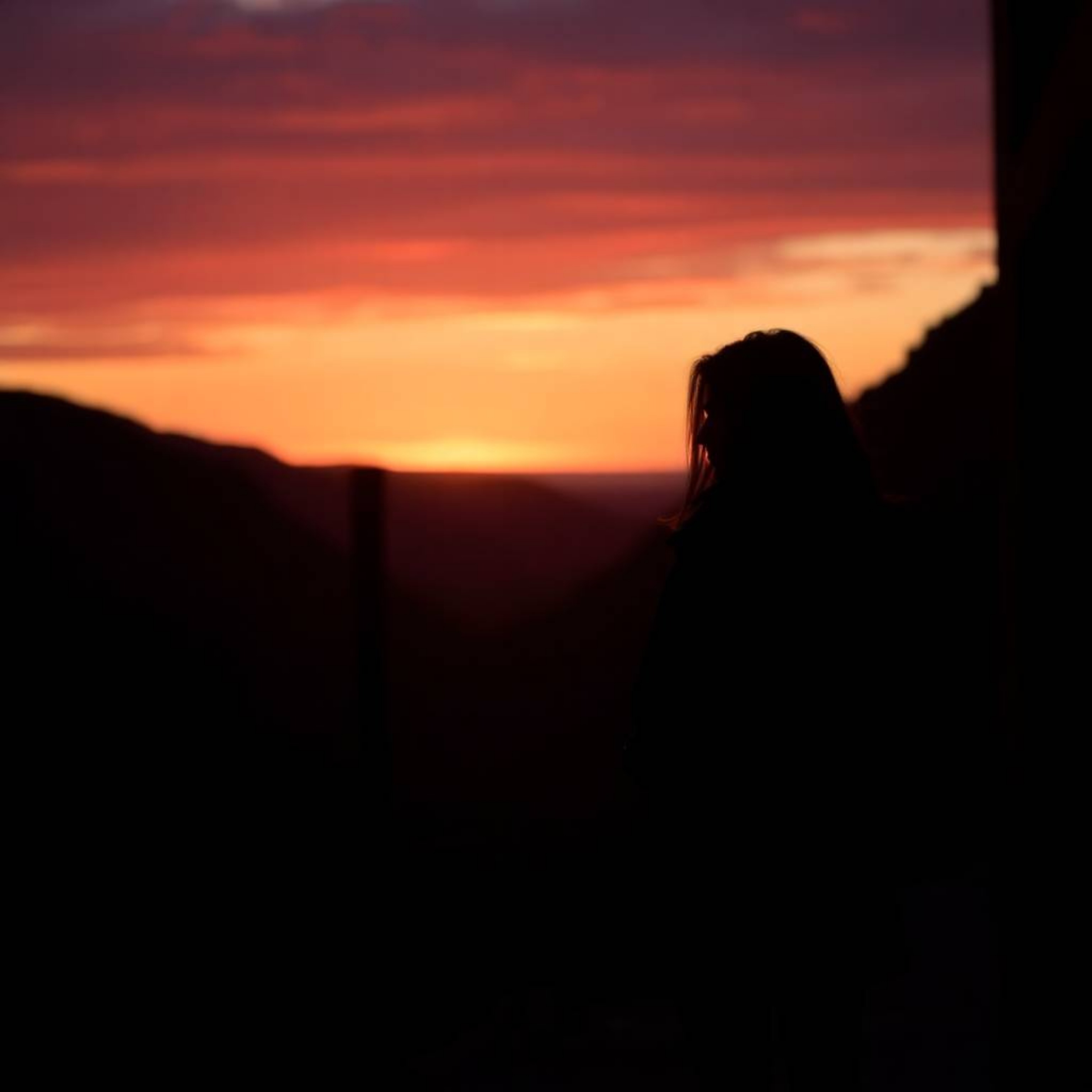 A sophisticated and elegant candid street photograph captures a breathtaking sunset over a quiet mountain valley, rendered in