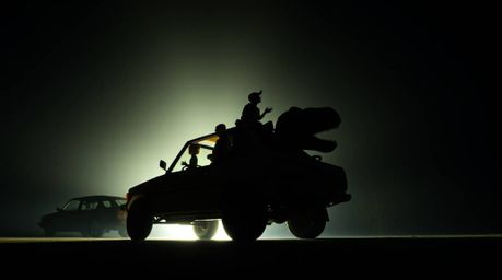 Experience a dramatic low-angle shot of a prehistoric family gazing upwards from their dinosaur car.  Deep shadows and high c