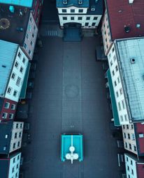 An overhead bird's eye view captures an empty town square with a top-down perspective, emphasizing the eerie silence and the 