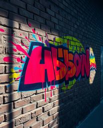 This image captures a vibrant graffiti-style artwork on a brick wall, featuring a dynamic array of colorful splashes illumina